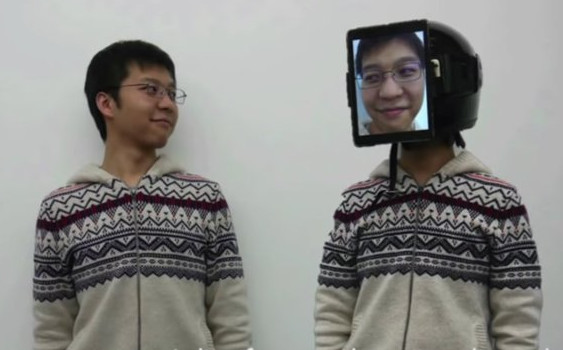 two people, one with an iPad in front of their face, showing the other person