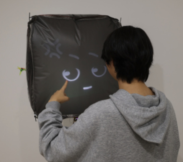 a guy poking at a big helium balloon with a projected cartoon face